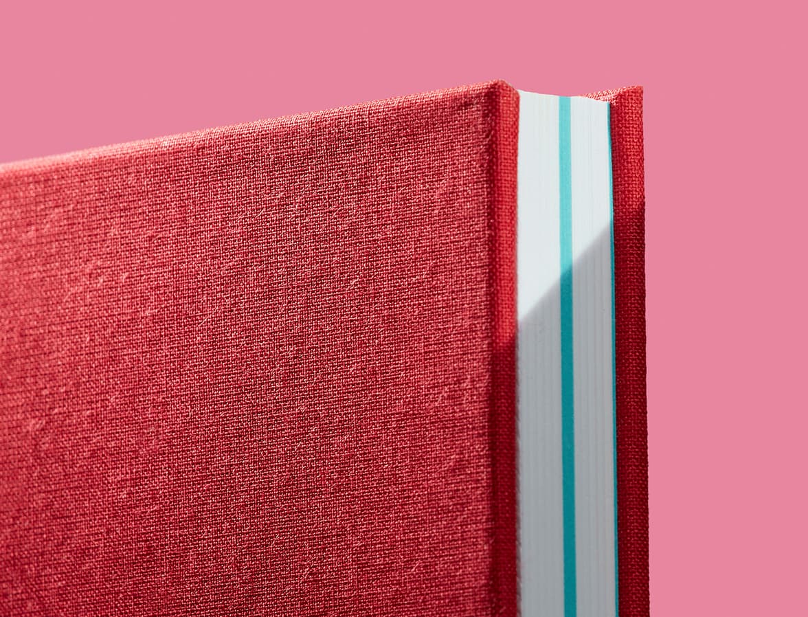 A detail image of the corner of a red hardcover notebook.