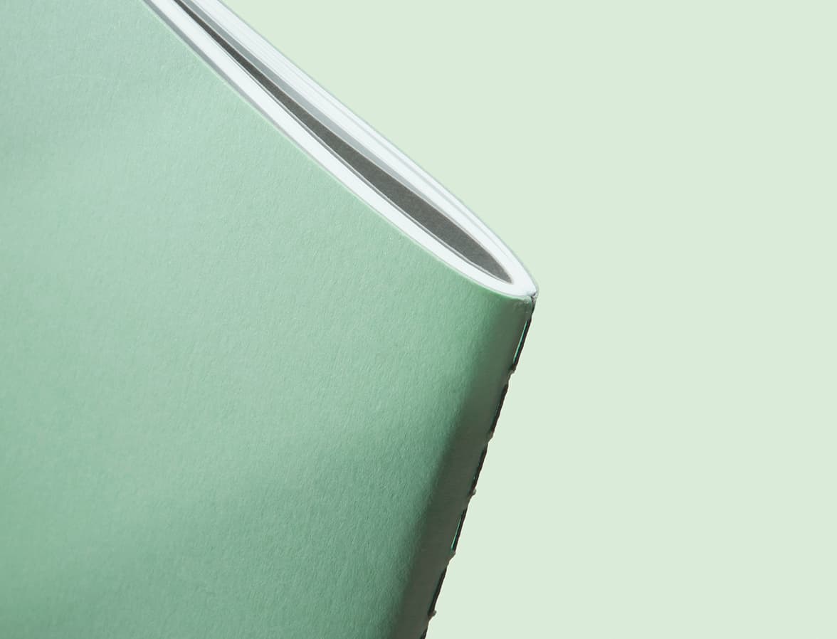 A close up image of the binding of a mint green softcover journal.