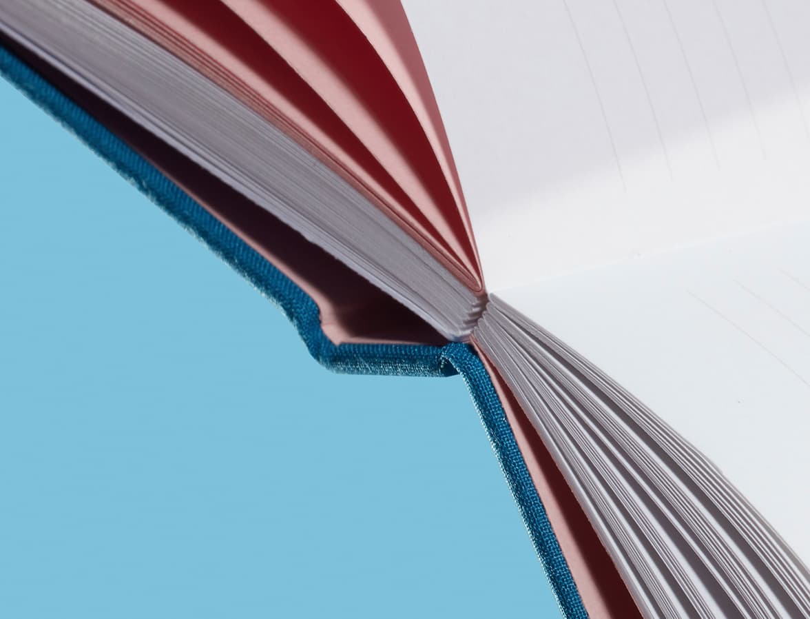 Detail image of an open hardcover notebook, focusing on the Swiss binding design.