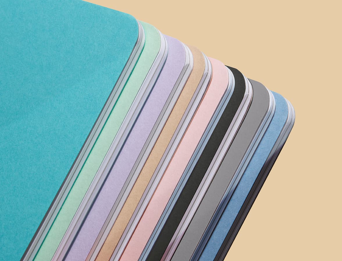 A close up image of a collection of softcover journals, varying in colour.