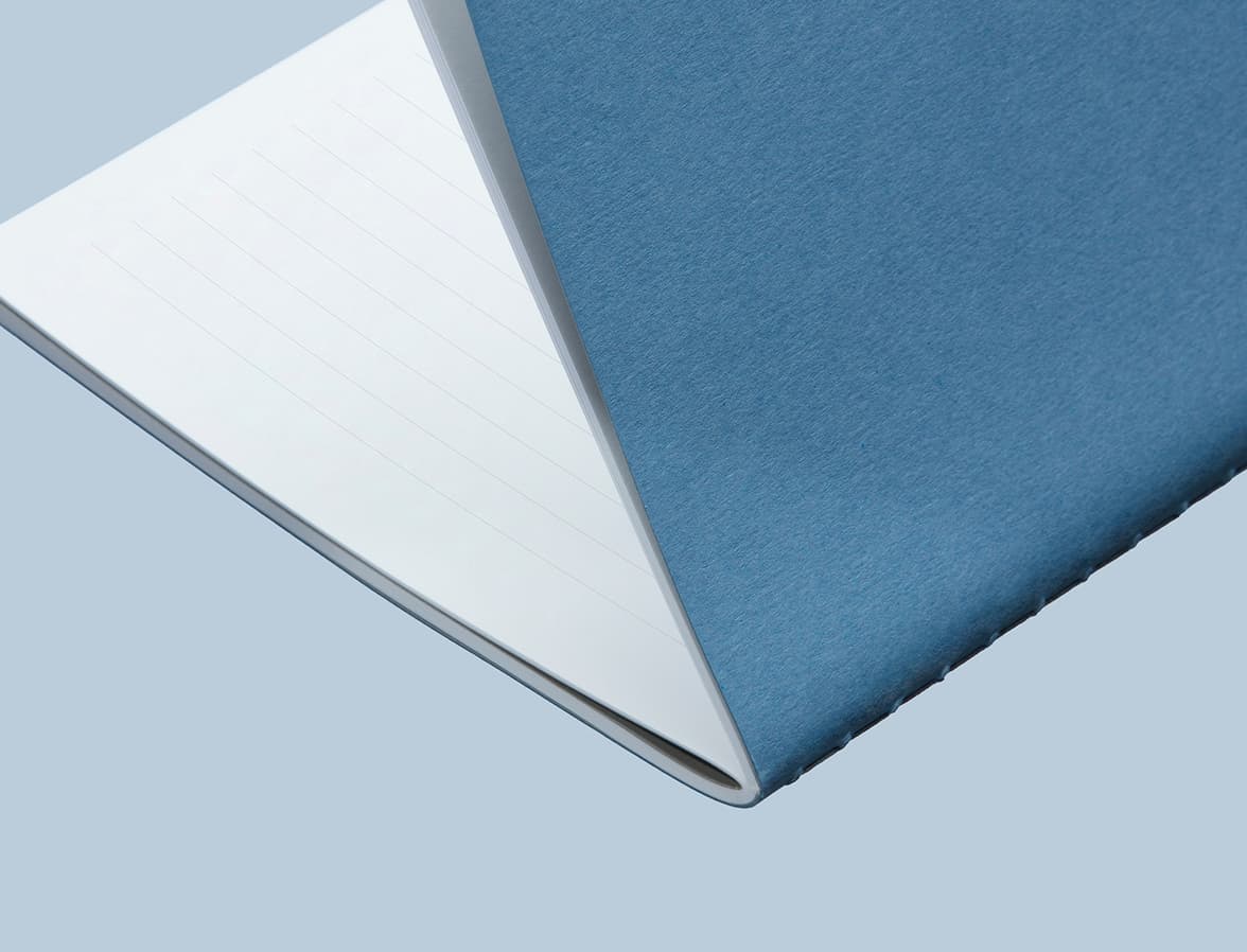 A close up image of a half open steel blue softcover journal with lined pages.
