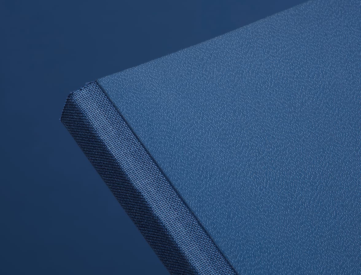 A close up of the top corner of a midnight blue softcover notebook.