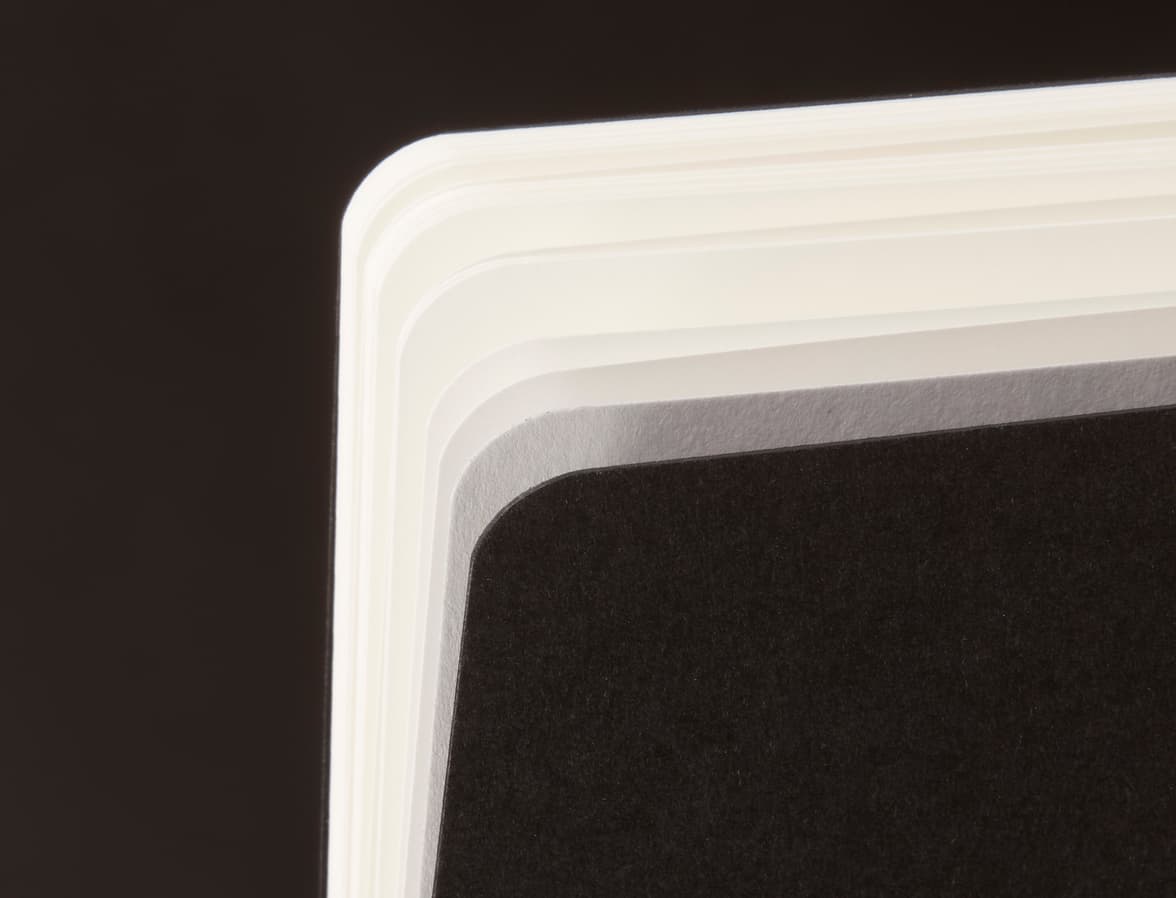A close up image of the page corners of a black tape bound notebook.