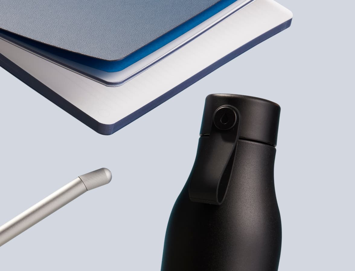 A collection of products including a softcover notebook, a pen and a water bottle.
