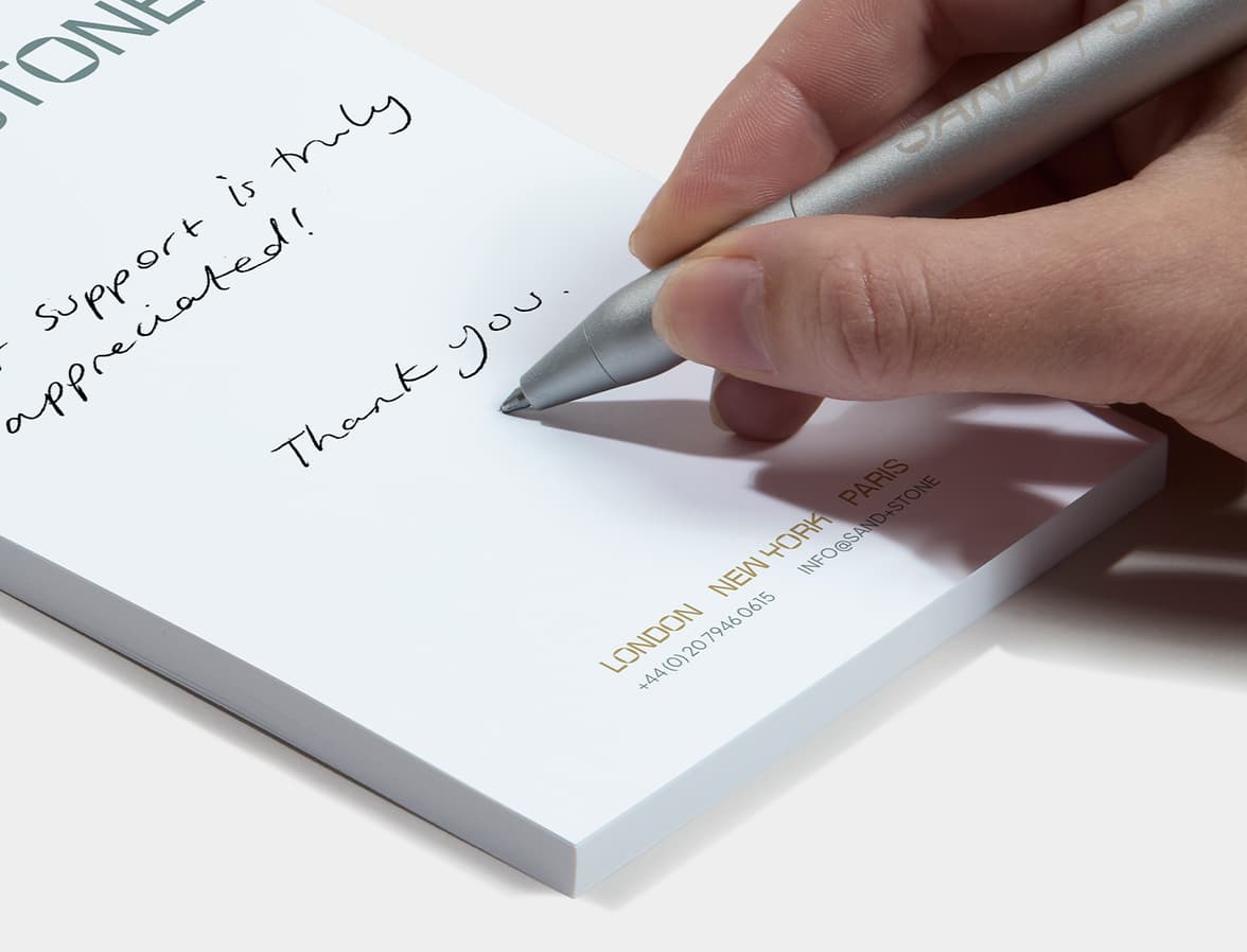A lifestyle image of a person writing on a customized notepad.