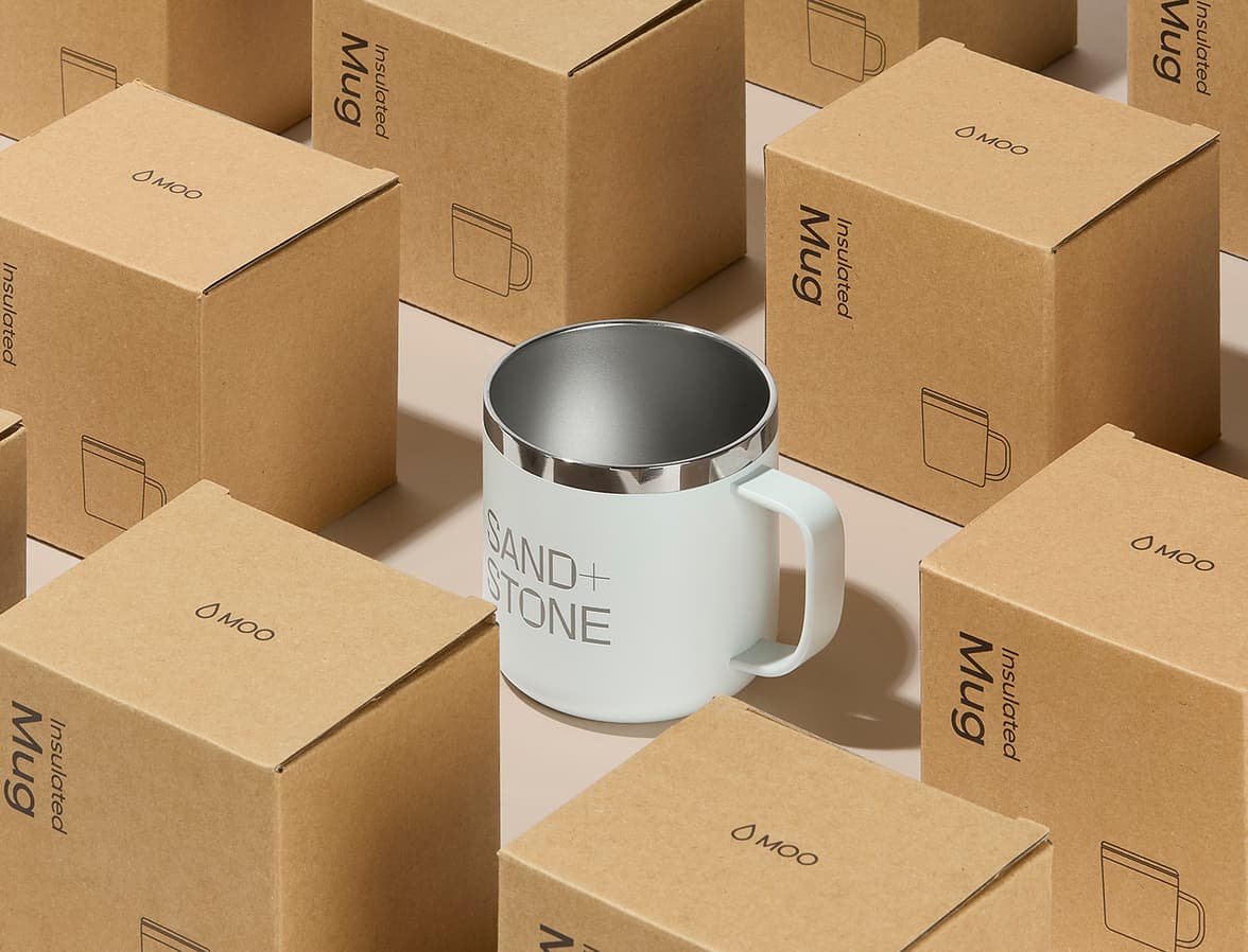 The cloudy grey insulated mug surrounded by the mug packaging boxes.