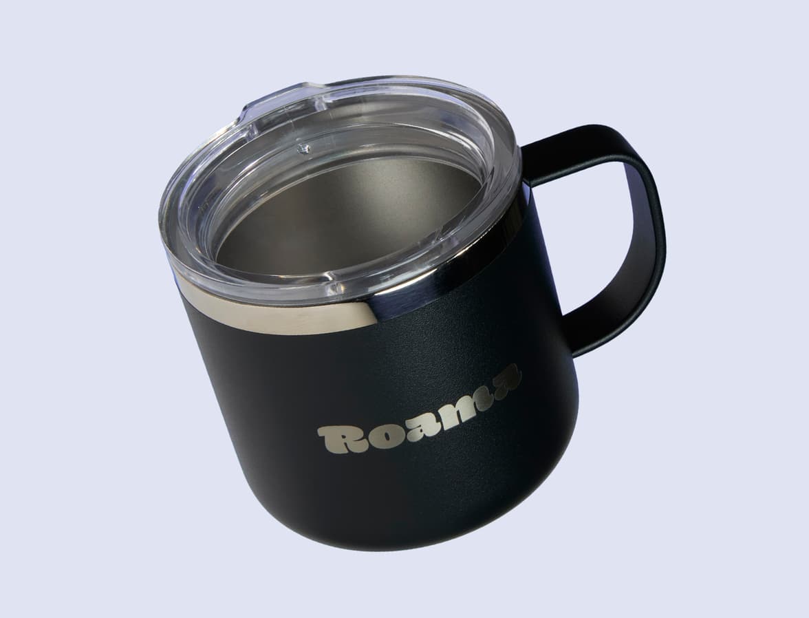 A black insulated mug with customised branding in front of a lilac background.