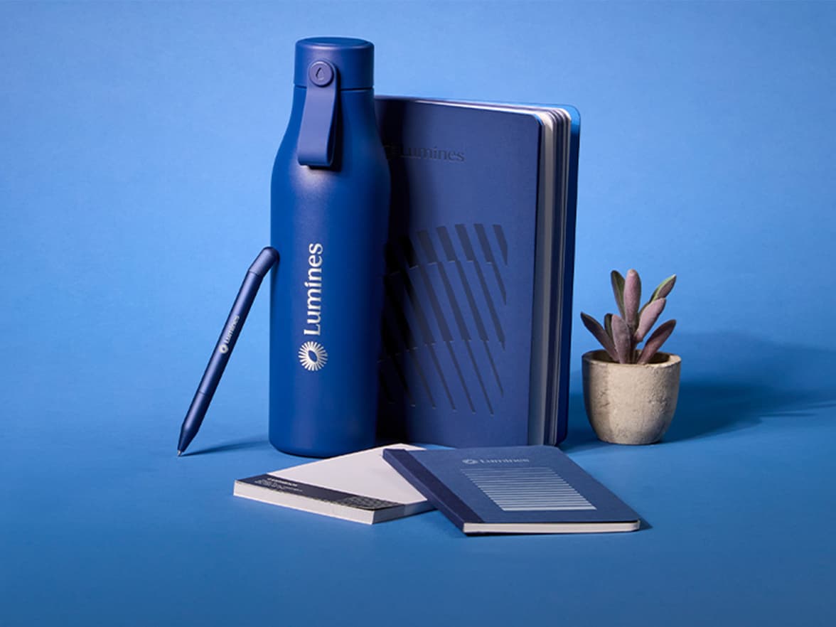 A collection of blue branded merchandise, including a water bottle, pen and notebook.