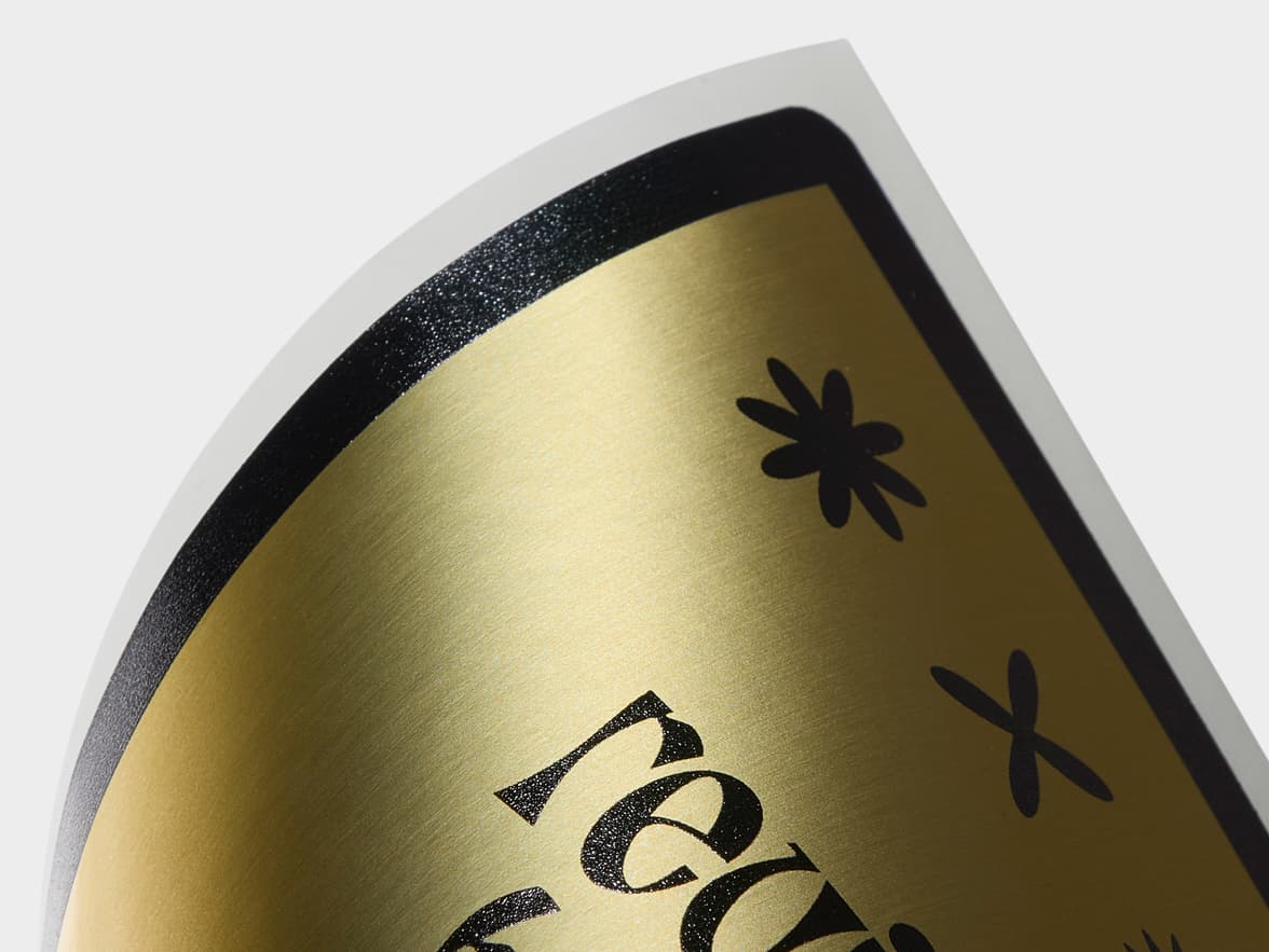 A close up image of the corner of a customized gold metallic sticker.