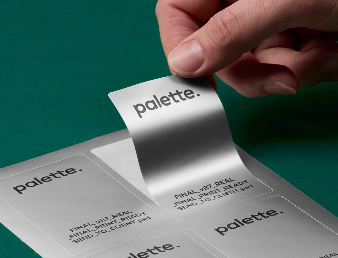 A hand peeling a sliver metallic stickers off of a sheet of stickers.