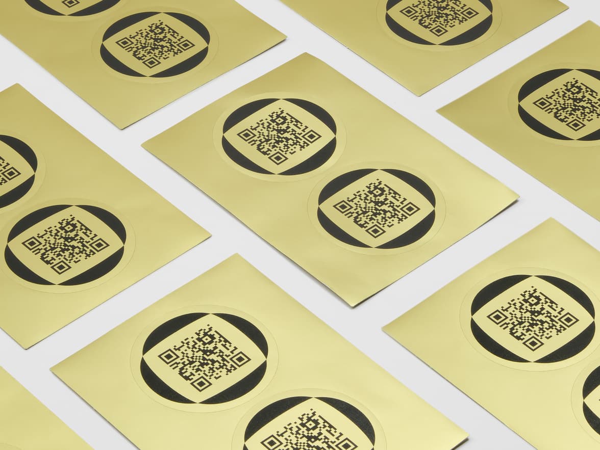 A collection of round gold metallic stickers with QR codes on them.