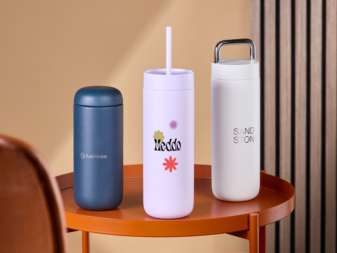 Three customized tumblers placed on an orange table.