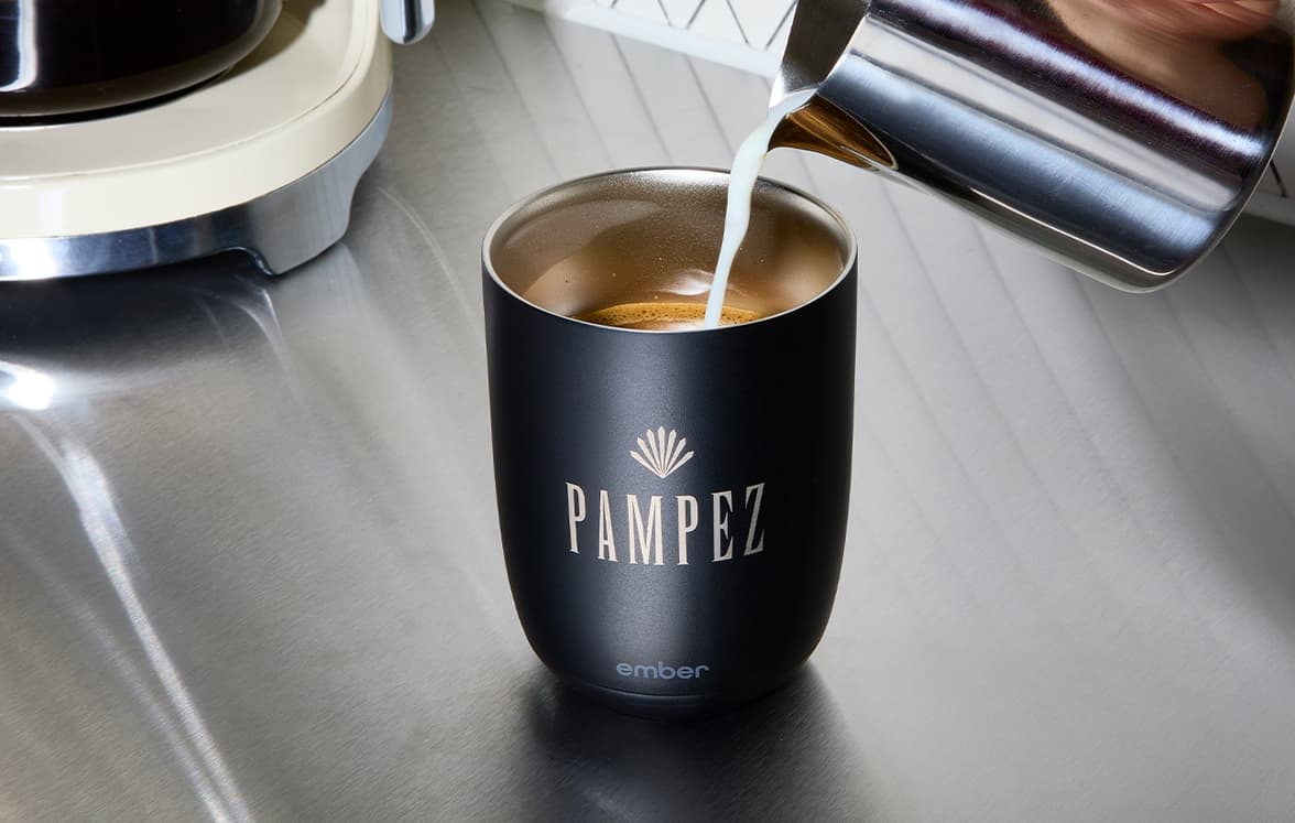 A customized black tumbler with milk being pour into it.