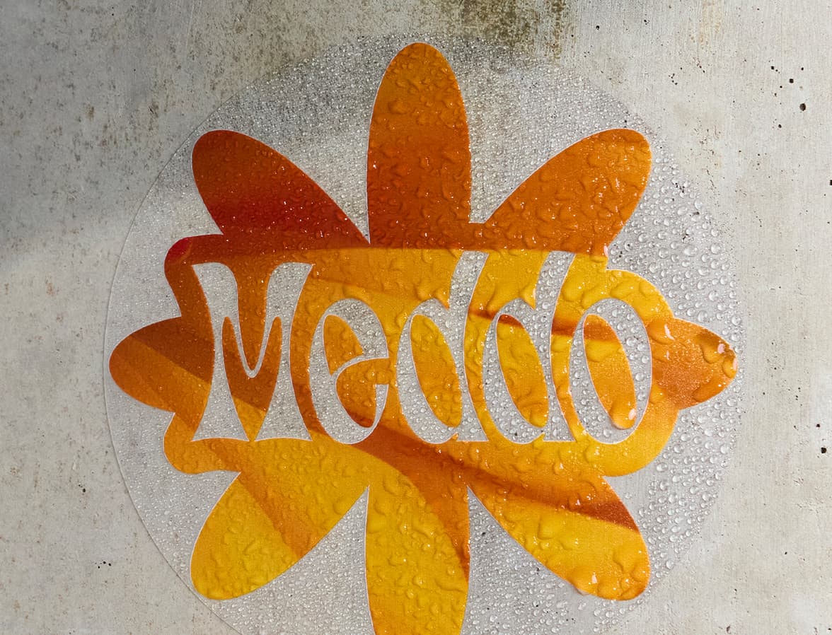 A customized clear round sticker with a large orange flower printed on it.