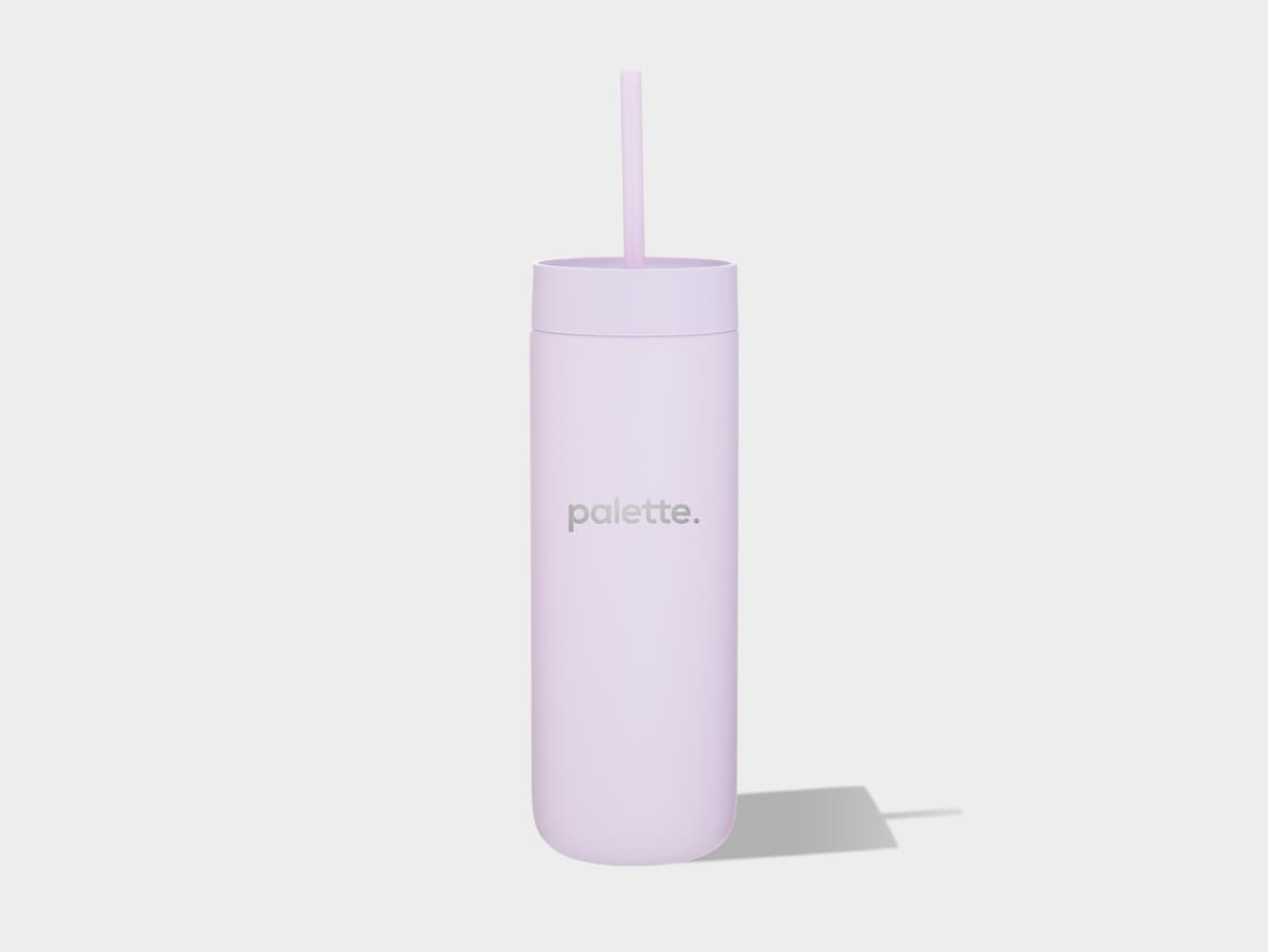 A light purple cylindrical tumbler with a matching lid and straw stands vertically on a light grey surface, casting a shadow to its right. The word "palette." is printed in a subtle grey font on the front of the tumbler.
