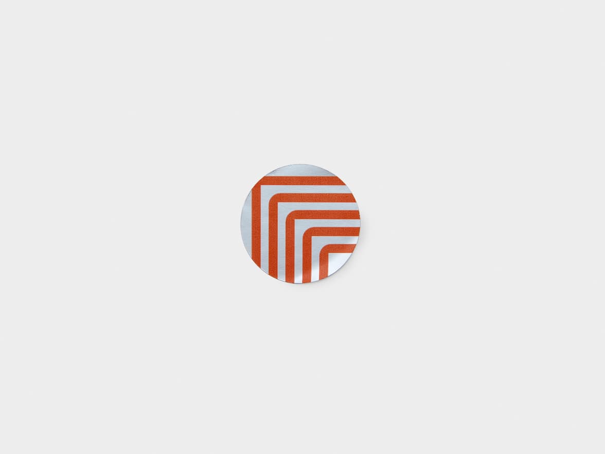 A round silver metallic sticker with orange customization.