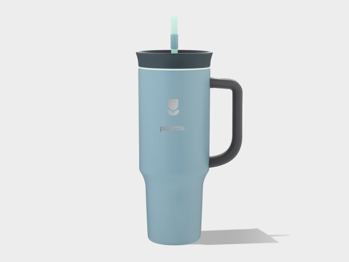 Light blue insulated tumbler with a dark grey handle and lid, and a light green straw, featuring the "palette." brand logo.