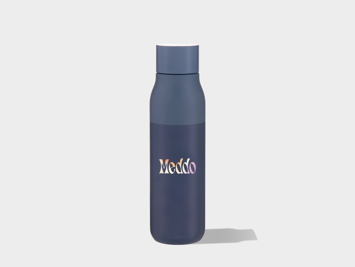 A slate blue water bottle with a white rimmed lid stands upright on a light gray surface, casting a soft shadow to its right. The word "Meddo" is printed on the lower half of the bottle in a colorful gradient.