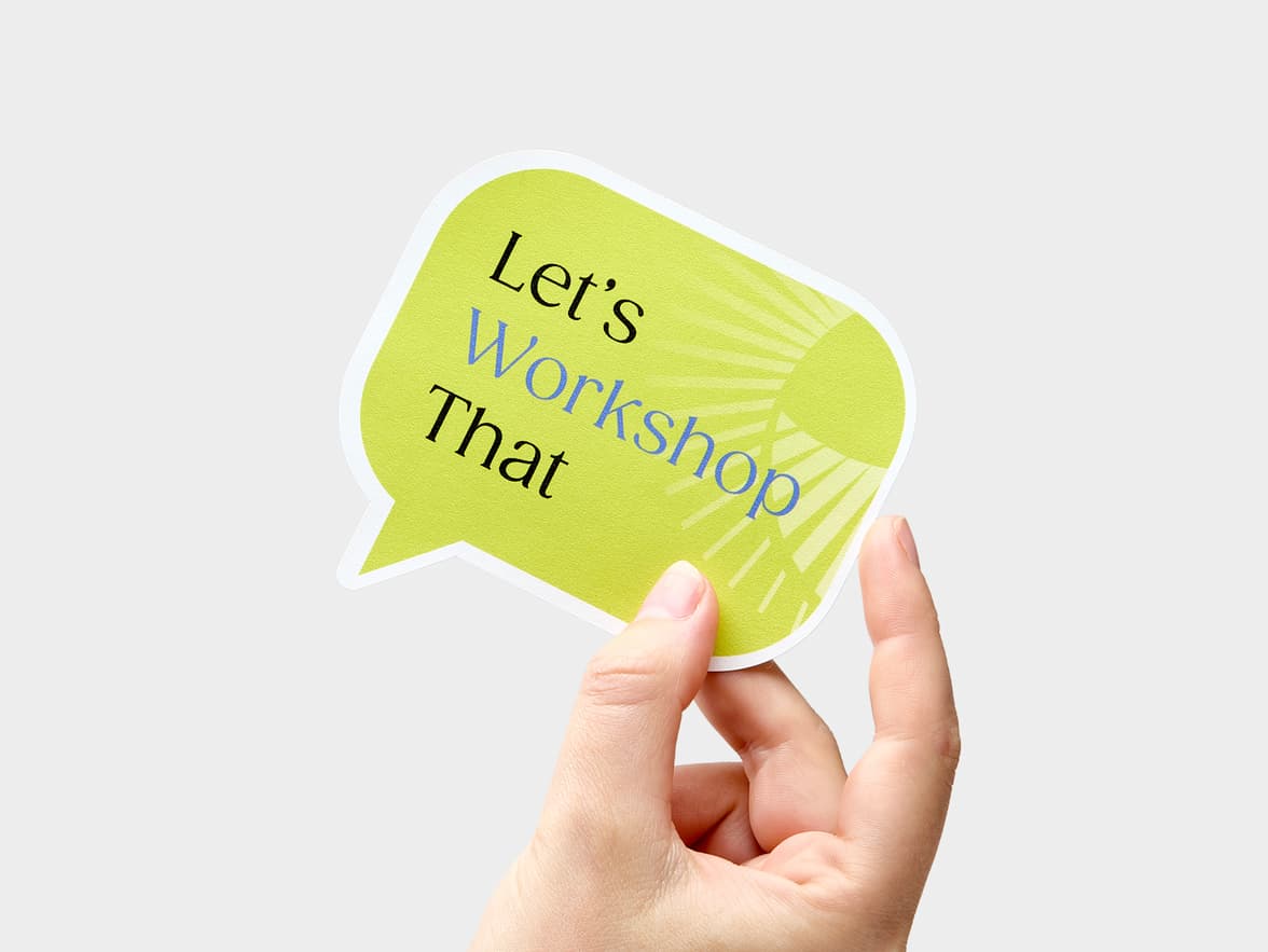 A hand holding a speech bubble shaped sticker.