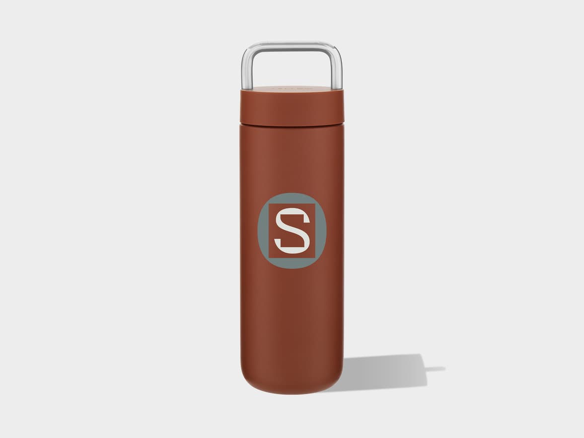 A brown tumbler with a silver handle and an S logo on its side.