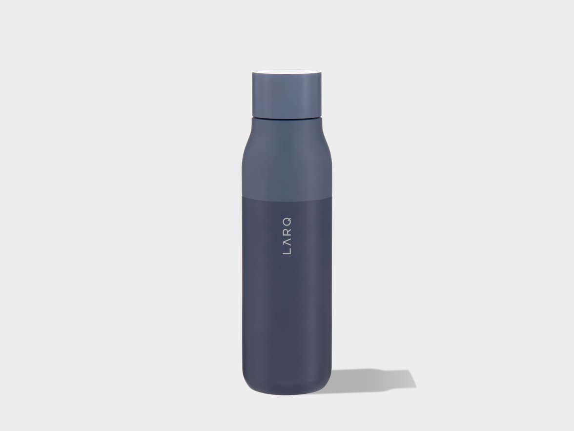 A two-toned LARQ water bottle, with a lighter blue-grey cap and upper section, and a darker blue-grey body featuring the vertical 'LARQ' logo. The bottle stands upright on a light grey surface, casting a shadow to its right.