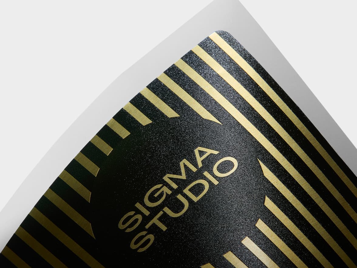 A close up image of the corner of a rectangular gold metallic sticker with black stripes.
