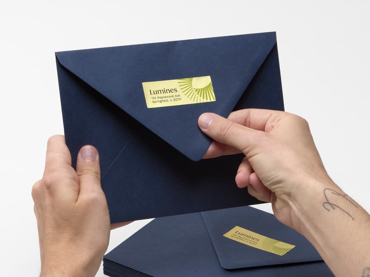 A hand holding a round gold metallic sticker with customization.