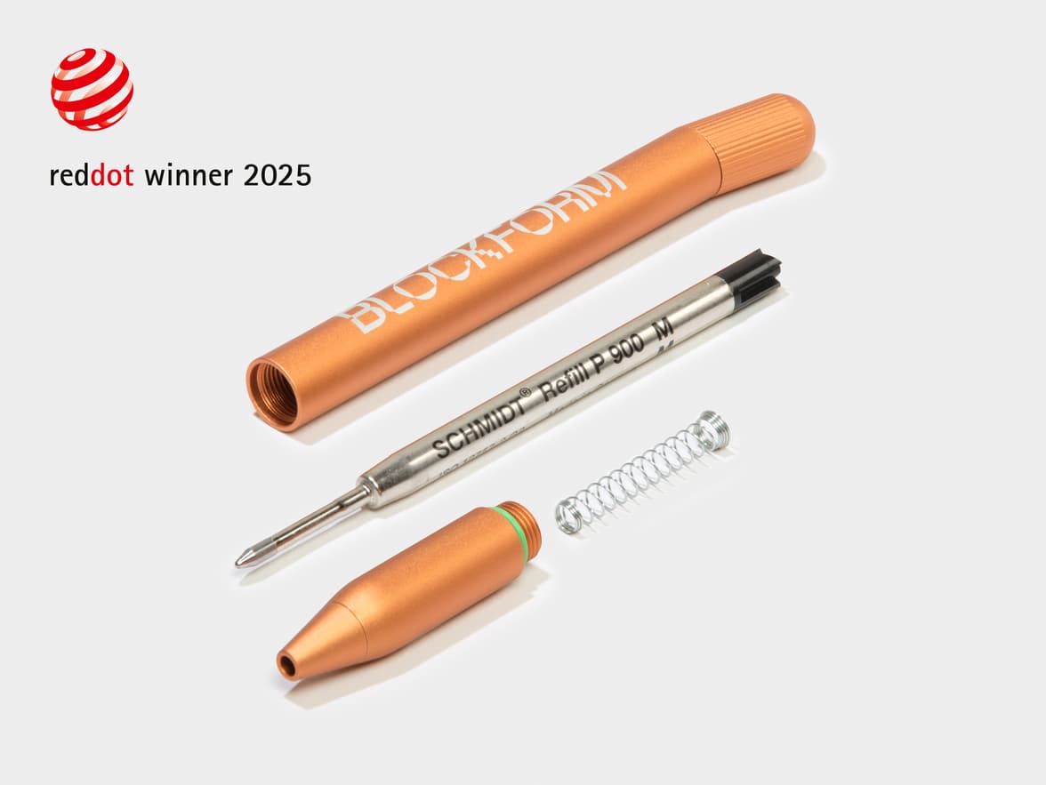 A dismantled orange MOO Twist Pen with a red dot design award logo in the top left corner.