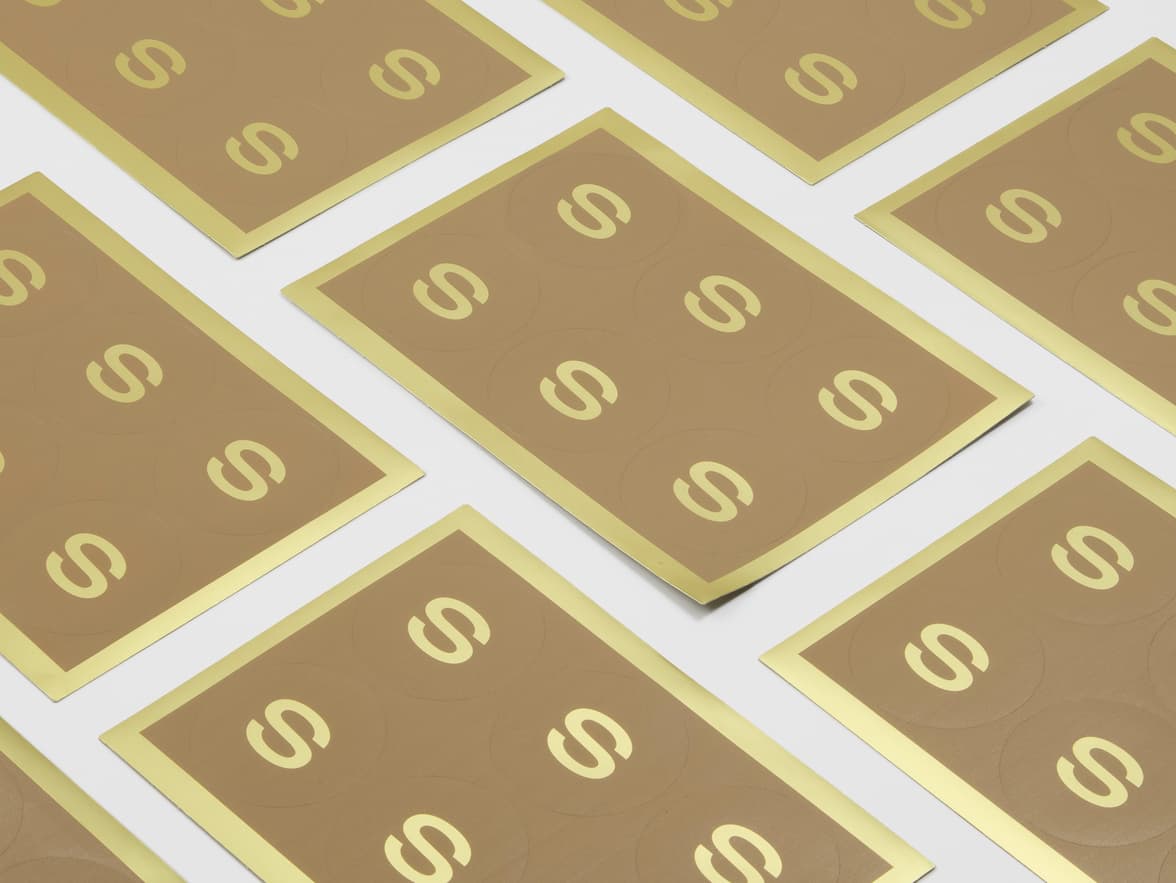 A collection of sheets with round gold metallic stickers on them with customization.