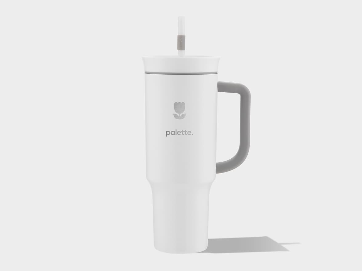 White tumbler with gray handle and straw, featuring a floral logo and "palette." branding.