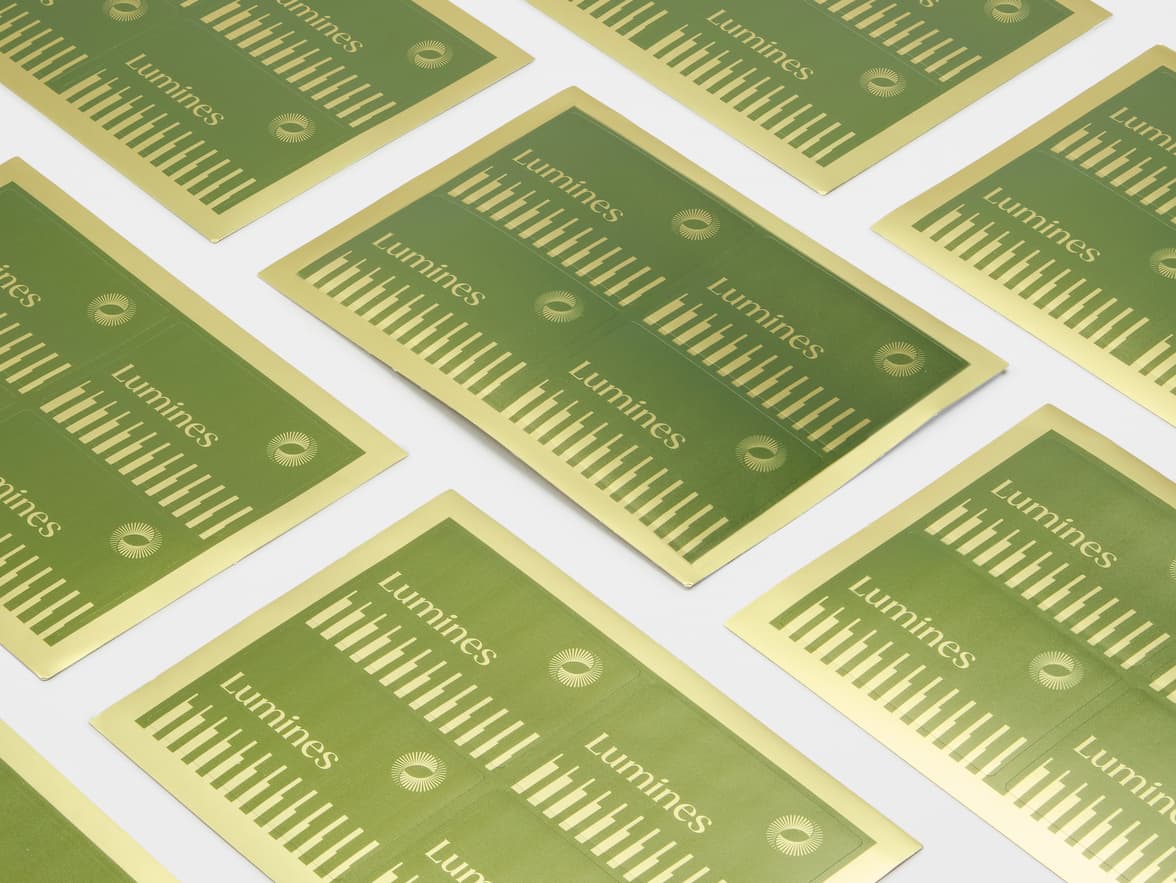 A collection of rectangular gold metallic stickers with green customization on sheets.